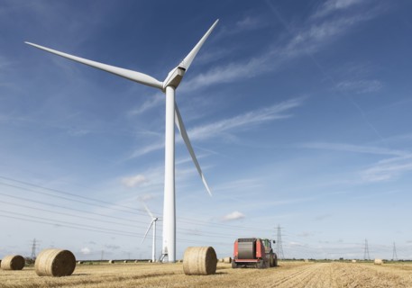 Bales of hay and tractor near wind turbine
