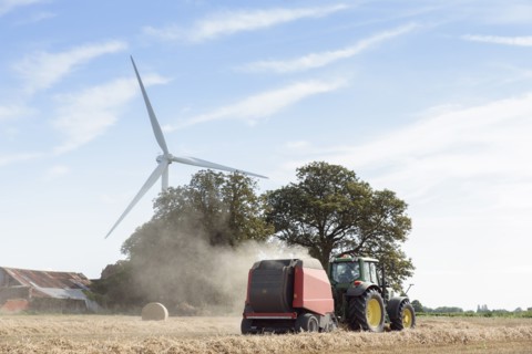 Caucasian man driving tractor near wind turbine
