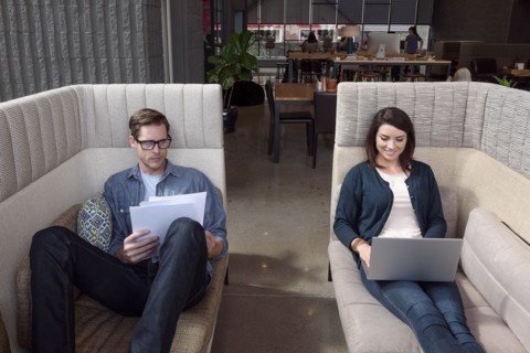 Caucasian couple on sofas using laptop and reading paperwork