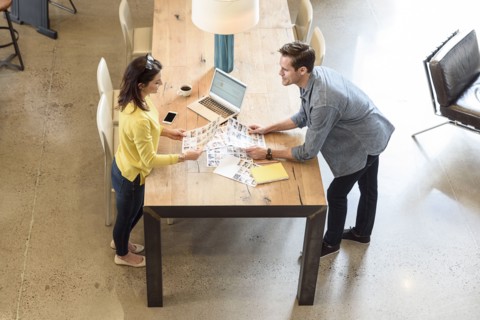 Caucasian man and woman examining photographs at table
