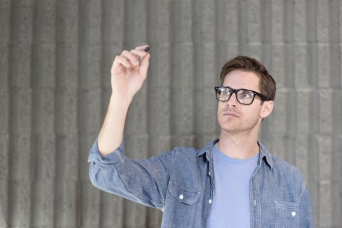 Caucasian man writing on glass wall