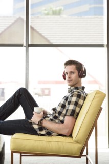 Caucasian man drinking coffee and listening to headphones