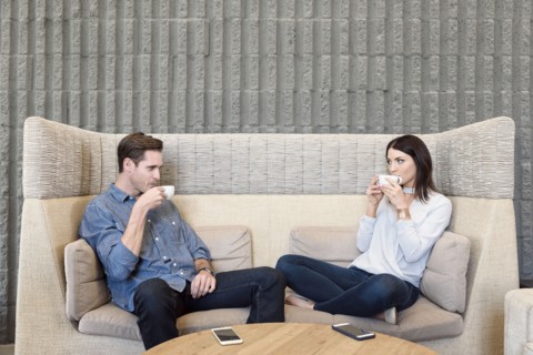 Caucasian couple relaxing on sofa drinking coffee
