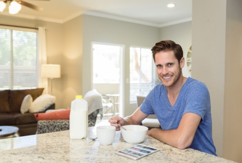 Portrait of smiling man eating bowl of cereal in morning