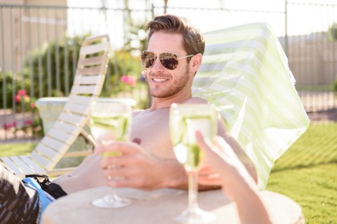 Caucasian couple relaxing in lounge chairs holding drinks
