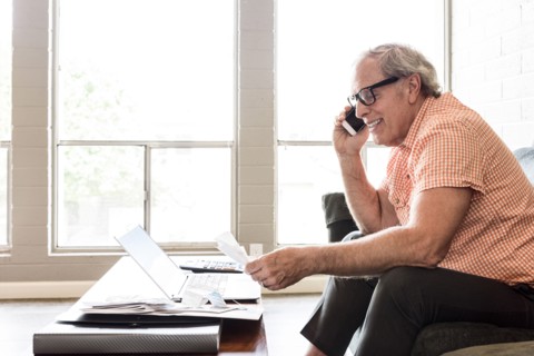 Smiling and Caucasian man sitting on sofa talking on cell phone
