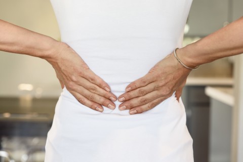Hands of mixed race woman rubbing lower back
