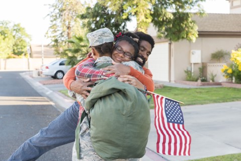 Black woman soldier hugging man and daughter