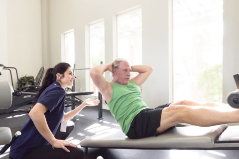 Caucasian trainer watching man doing sit-ups