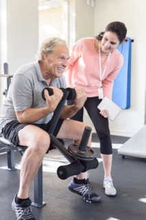 Caucasian trainer watching man strengthen arms