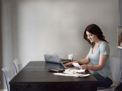 Caucasian woman holding receipt and using laptop