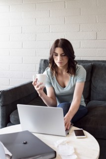 Caucasian woman drinking coffee and using laptop