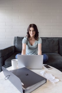 Caucasian woman sitting on sofa using laptop