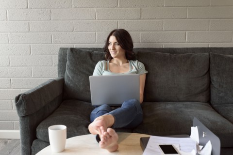 Caucasian woman sitting on sofa using laptop