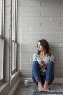 Caucasian woman sitting on floor texting on cell phone