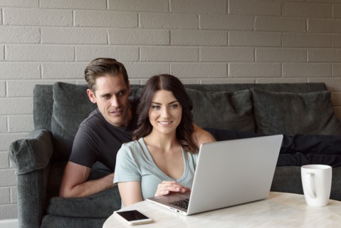 Caucasian couple on sofa using laptop