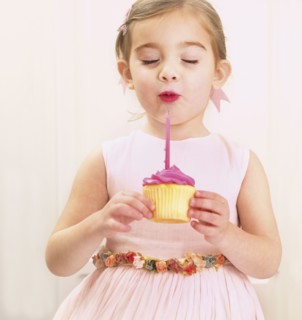 Young girl holding a birthday cupcake