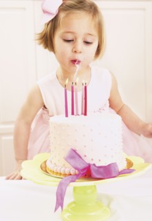 Young girl blowing out the candles on a birthday cake