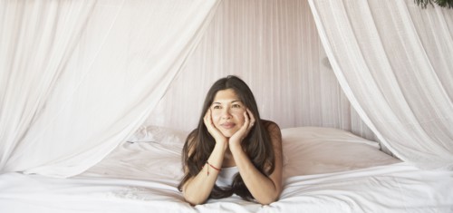 Young woman relaxing in a four-poster bed