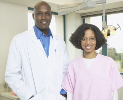 African male dentist with African female dental assistant smiling