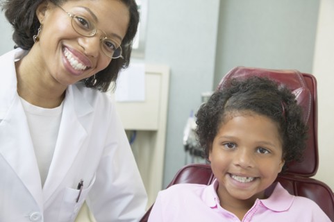 African female dentist examining young female patient