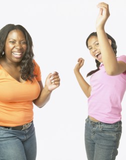 Studio shot of African mother and daughter dancing and laughing