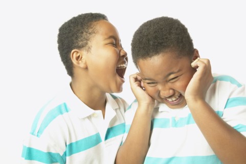 Young African boy yelling into twin brother's ear