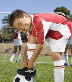 Mixed Race boy tying soccer shoe