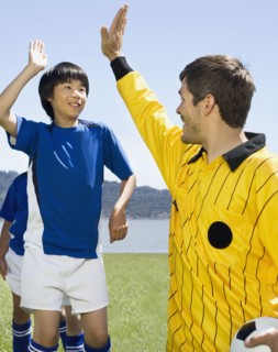 Asian boy high-fiving soccer coach