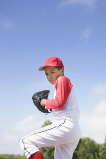 Mixed race boy in baseball uniform pitching in game