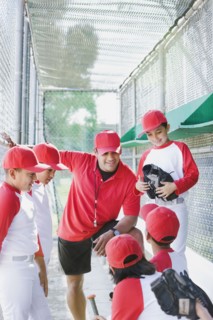 Multi-ethnic boys in baseball uniforms with coach in dugout
