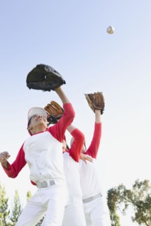 Multi-ethnic boys in baseball uniforms jumping to catch baseball