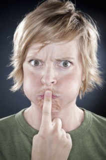 Caucasian woman holding finger over her mouth