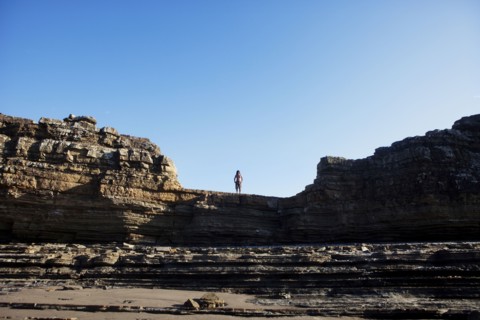 Asian man standing on cliff's edge