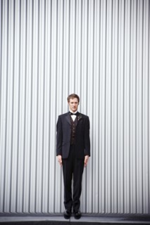 Serious groom standing near wall