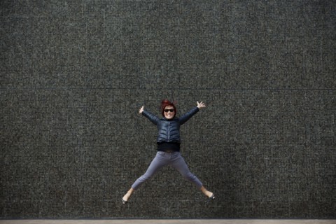 Korean woman jumping on city sidewalk