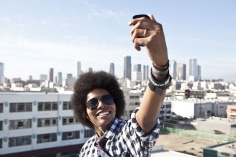 African American man taking cell phone picture from urban rooftop
