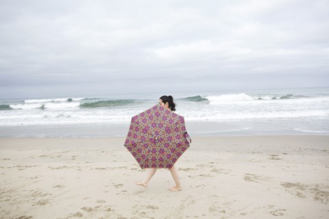 Woman walking with umbrella on beach
