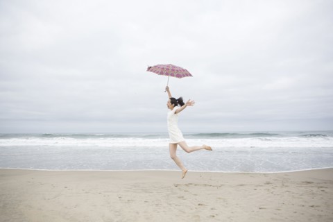 Woman playing with umbrella on beach