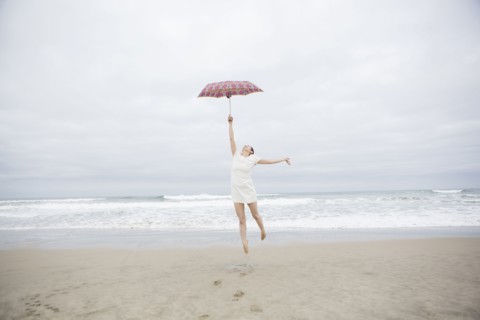 Woman playing with umbrella on beach