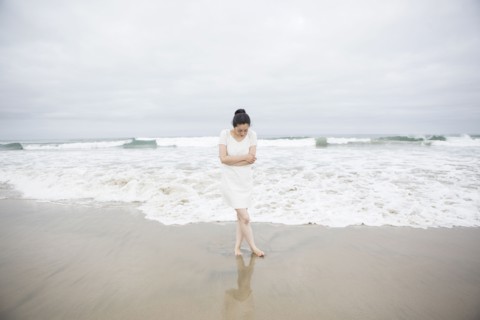 Woman standing near waves on beach