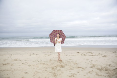 Woman laughing with umbrella on beach