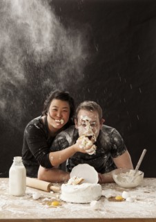 Woman shoving cake in face of boyfriend
