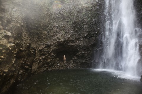Mixed Race woman standing near waterfall pool