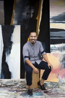Pacific Islander artist sitting with paintings