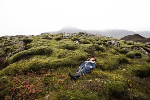 Caucasian woman laying on mossy rocks