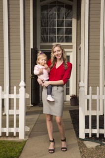 Caucasian mother posing near house with baby daughter