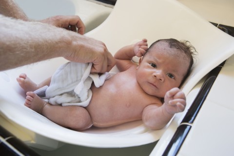 Man bathing mixed race baby
