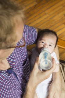High angle view of father bottle feeding baby