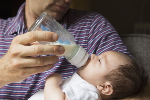 Close up of father bottle feeding baby